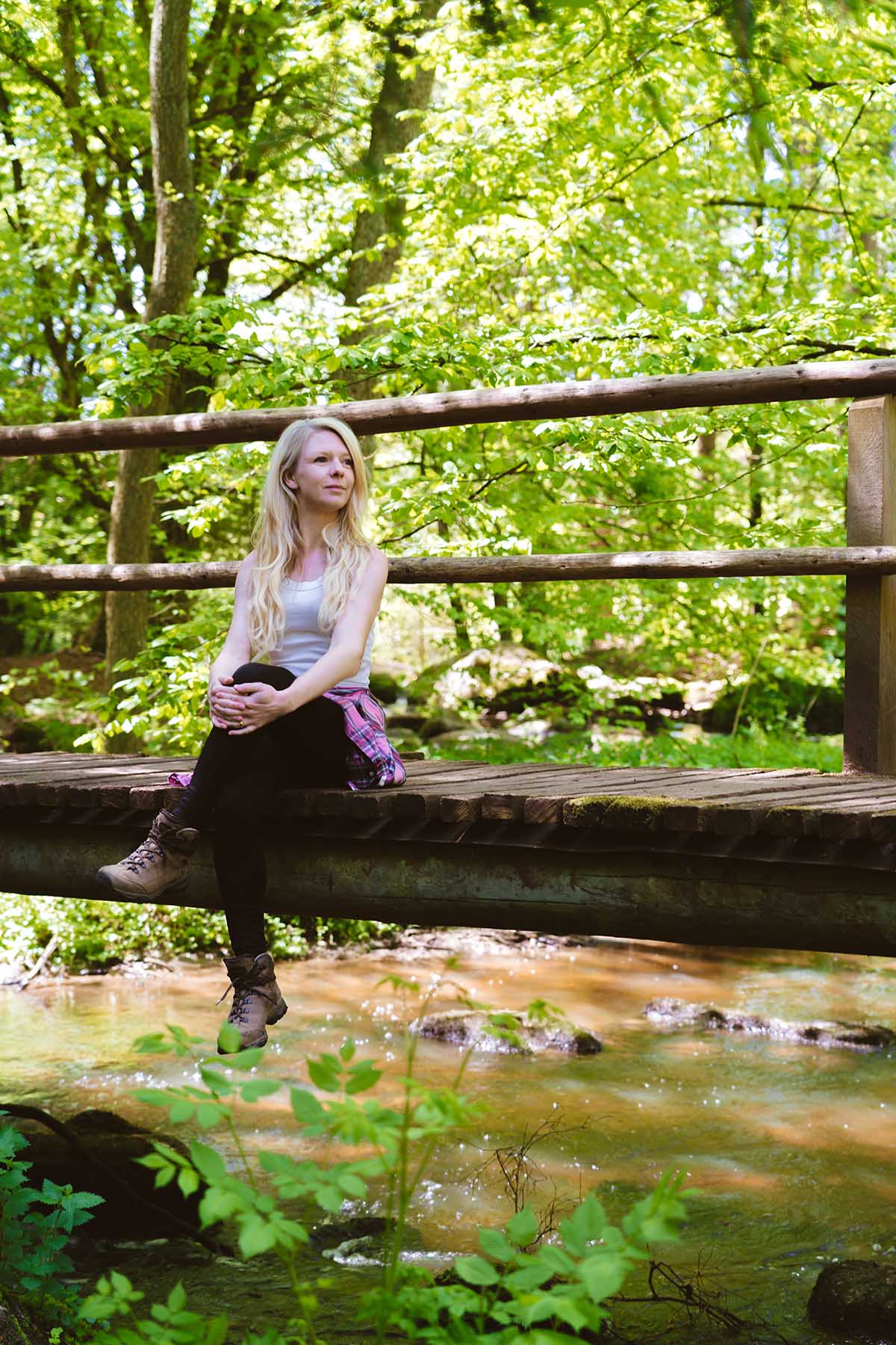 Frau sitzt auf Holzbrücke im Bayerischen Wald