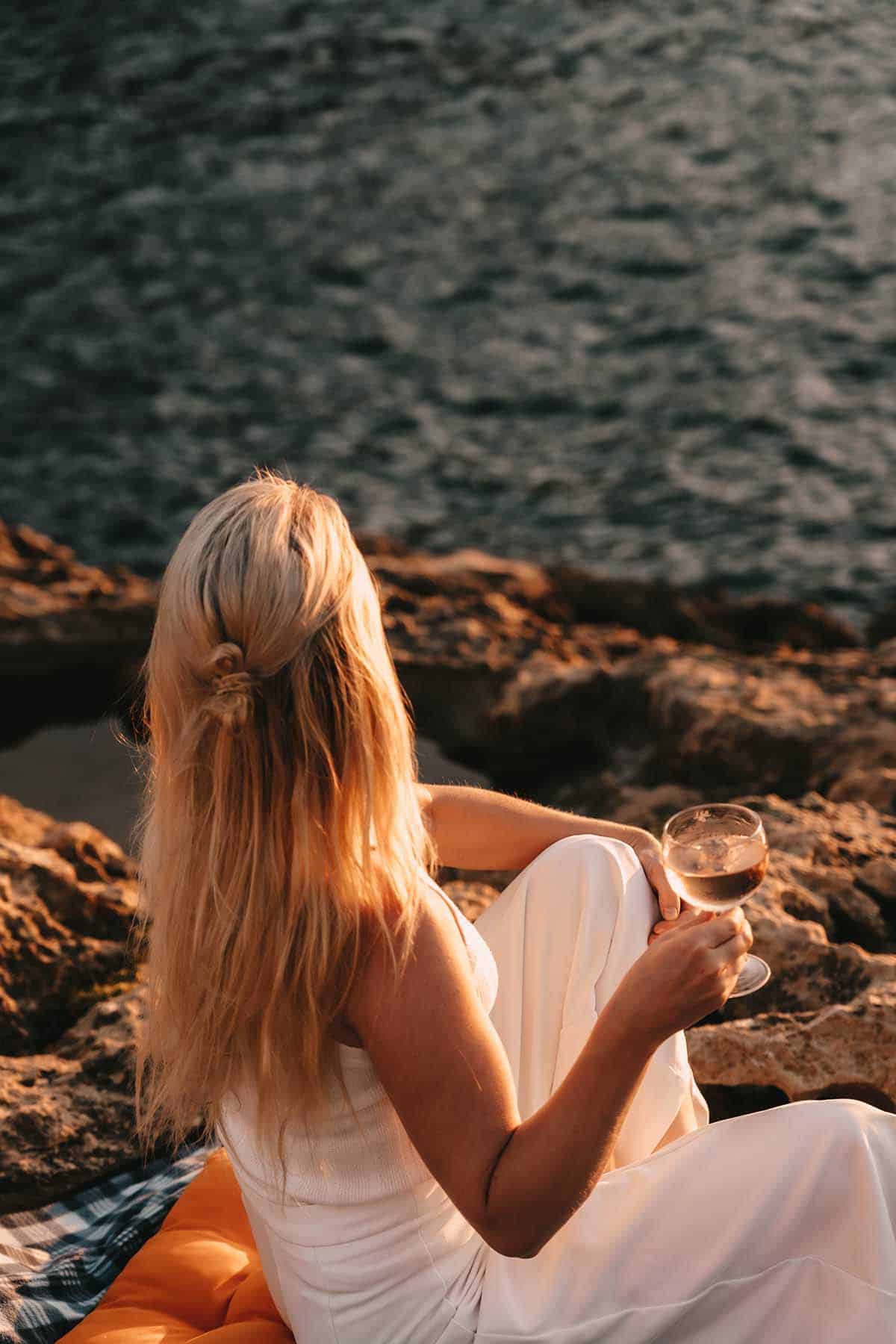 Frau trinkt Wein an der Xlendi Bay 